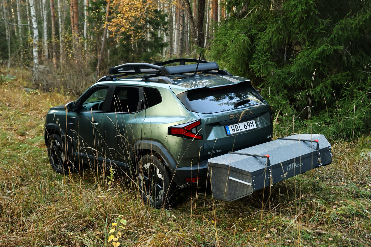 Dacia Duster med en IXTAbox bakbox på dragkrok monterad, parkerad på en skogsväg